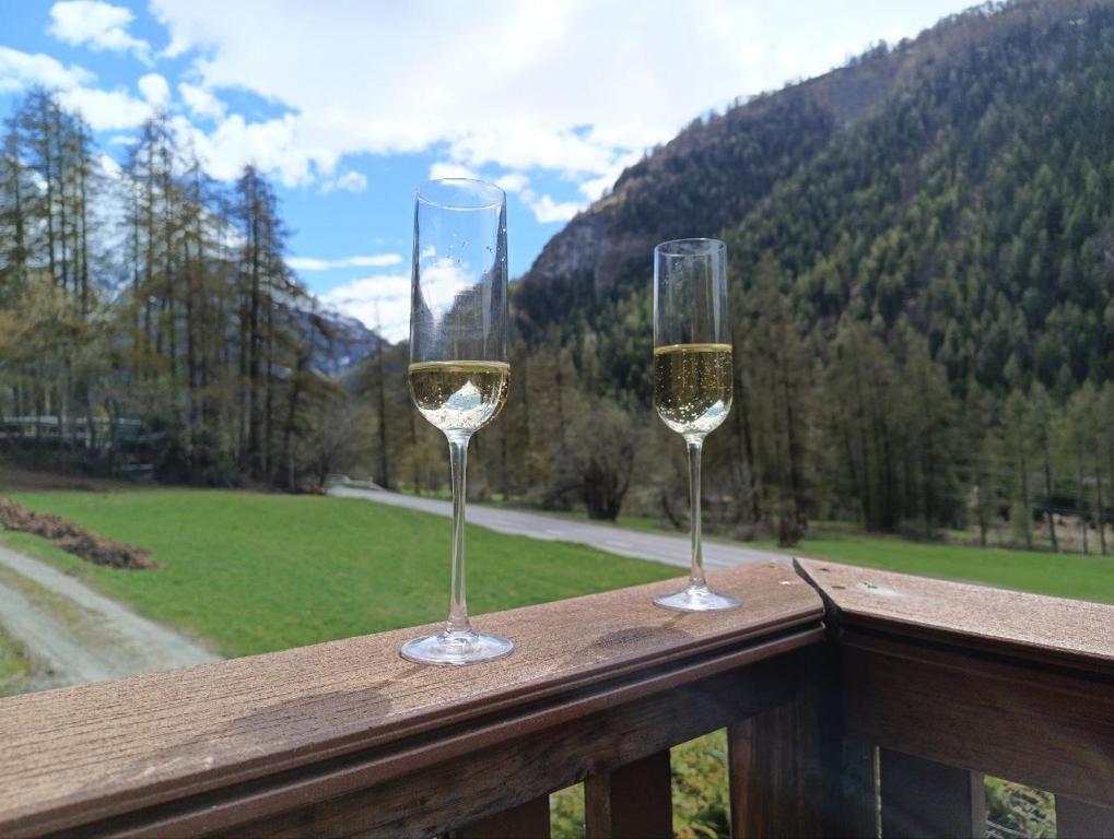 two glasses of white wine sitting on a balcony at Le chemin des étoiles in Evolène