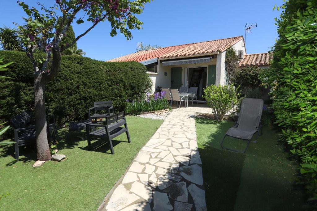 un jardin avec un banc et une maison dans l'établissement Maison fleurie quartier calme st Cyprien, à Saint-Cyprien