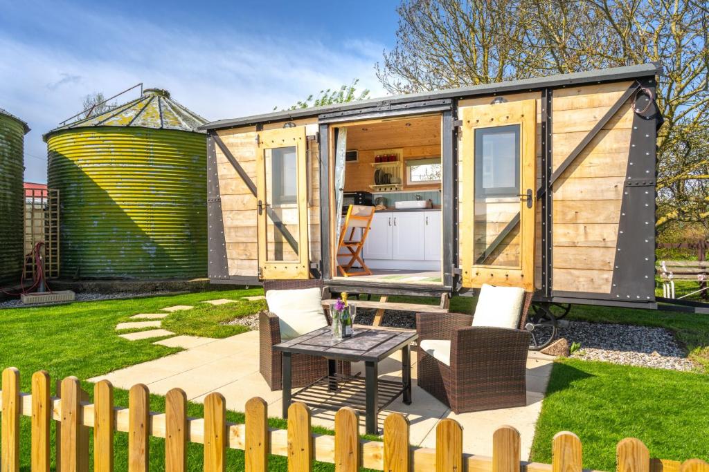 a tiny house with a table in a yard at Gin and Toffee Carriage in Thaxted