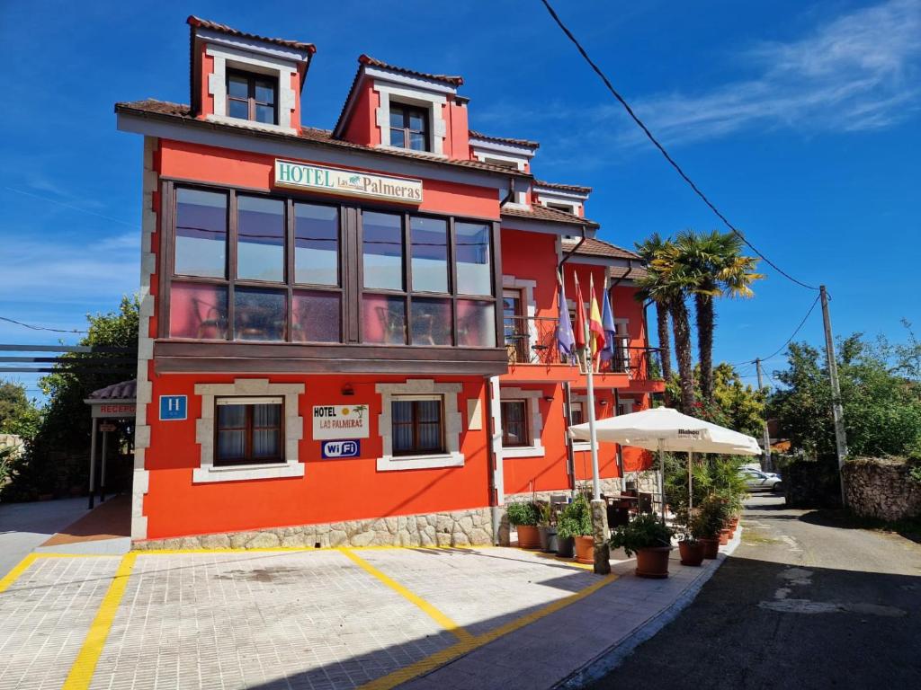 a red building with an umbrella in front of it at Hotel las Palmeras Suite in Celorio