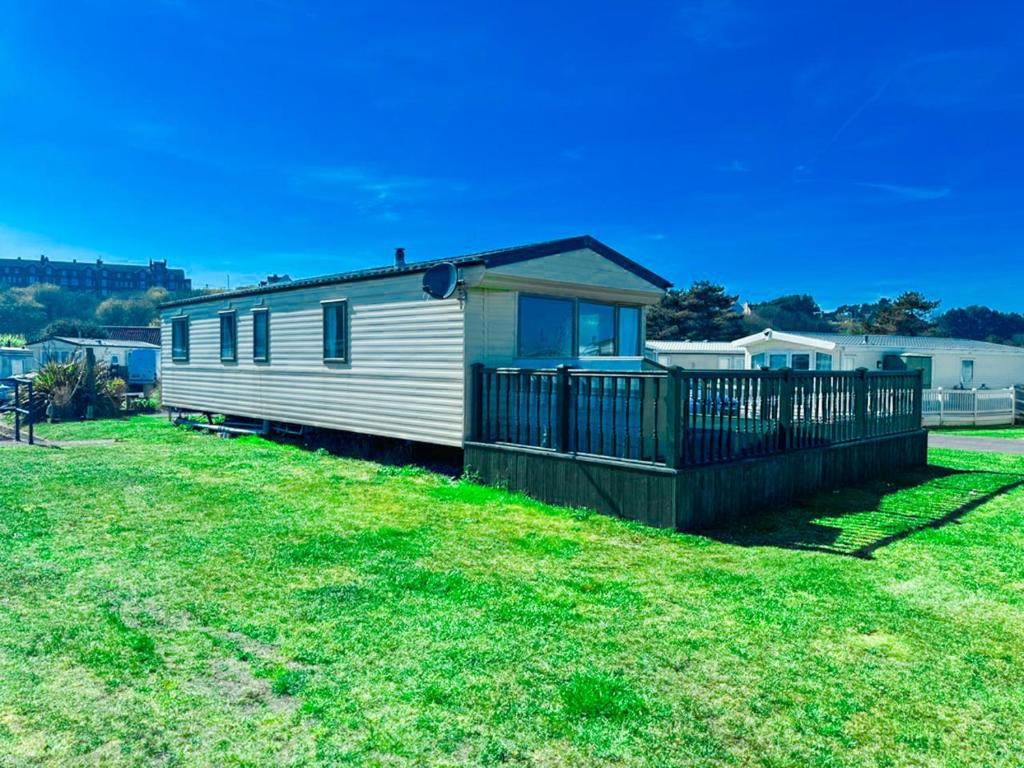 a small white house with a fence in a yard at Beachside Caravan Retreat In Lowestoft Sleeps 6 in Lowestoft