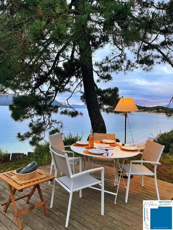 une table et des chaises sur une terrasse avec vue sur l'eau dans l'établissement Villa ACONIT - Les pieds dans l'eau, à Lecci