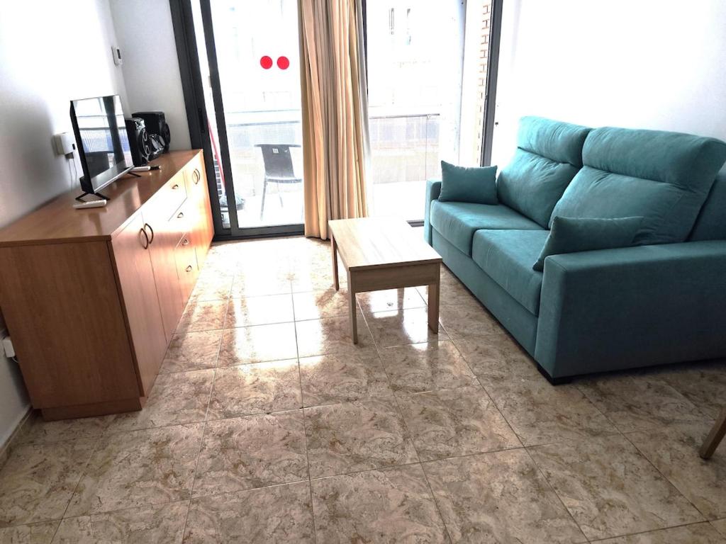 a living room with a blue couch and a table at Seawolf Apartment, Lloret de Mar in Lloret de Mar