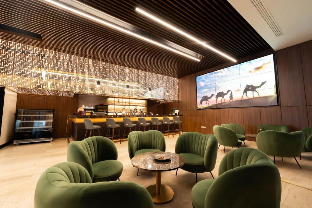 チュニスにあるHotel Royal ASBU Tunisの緑の椅子と大きなスクリーンのあるレストラン