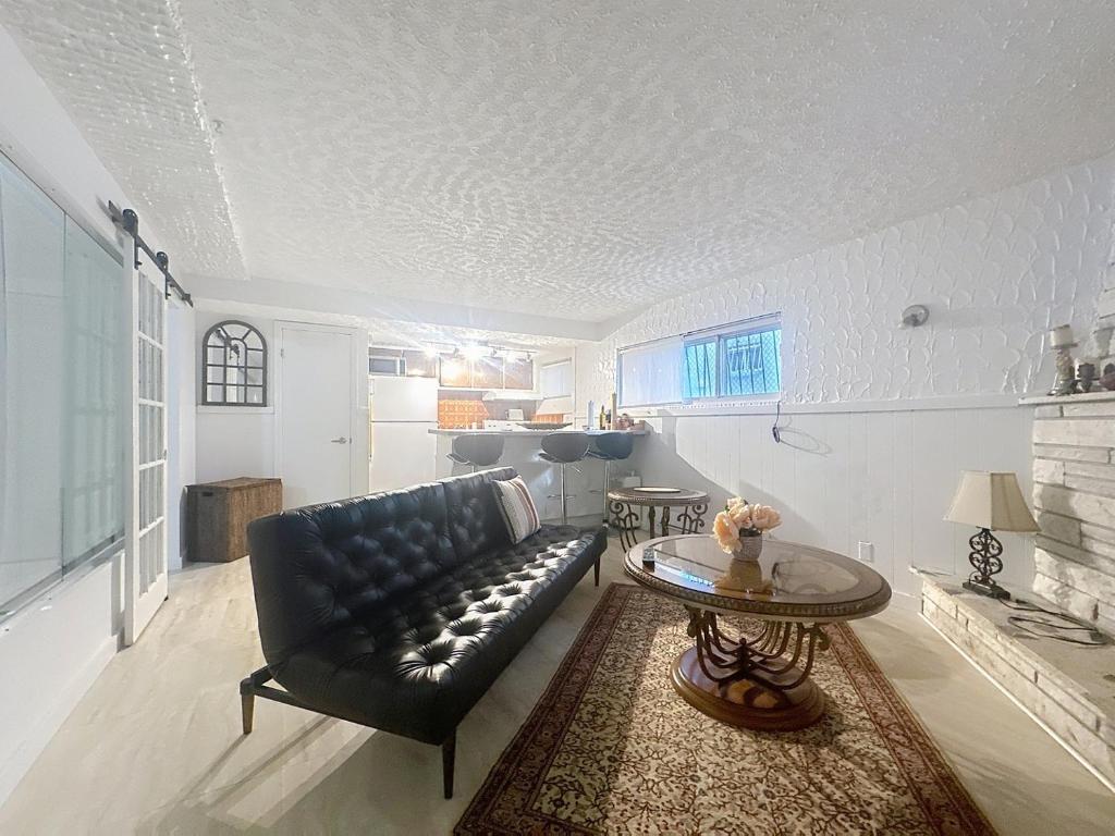 モントリオールにあるLogement 1 pièce Cozy - Parfait pour Courts Séjoursのリビングルーム(黒い革張りのソファ、テーブル付)