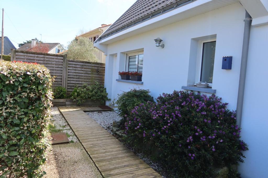 une maison blanche avec des fleurs violettes et une passerelle en bois dans l'établissement Petite Maison bord de mer, à Pornichet