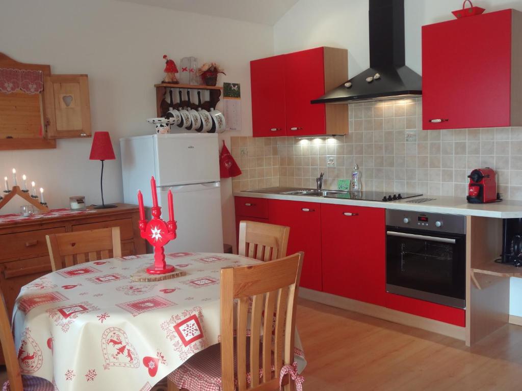 une cuisine avec des placards rouges et une table avec un chiffon rouge dans l'établissement COUP de COEUR - bord et vue lac Gérardmer, à Gérardmer