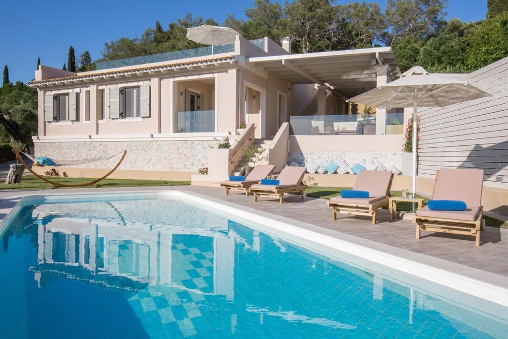a villa with a swimming pool in front of a house at Villa Pelekas in Mesochórion