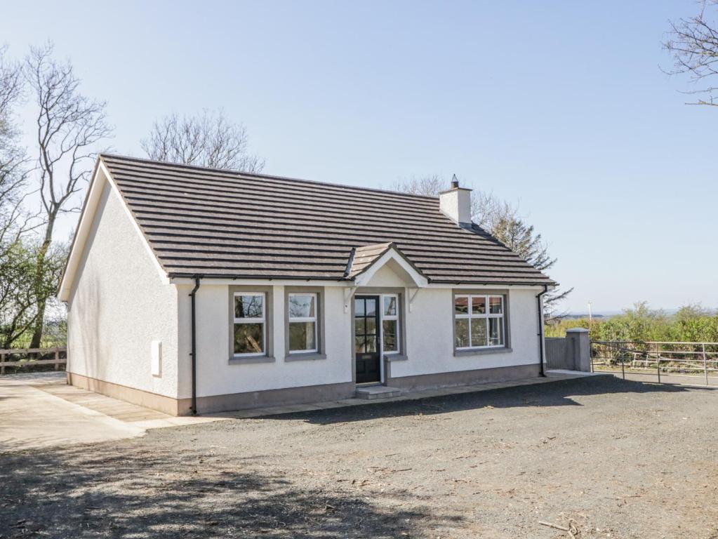 ein kleines weißes Haus mit schwarzem Dach in der Unterkunft Hill House in Ballymoney