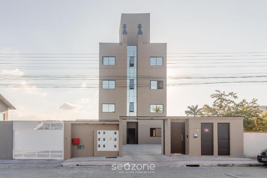 a tall brown building with a garage in front of it at CTDs - Apartamentos no Centro de Penha! in Penha