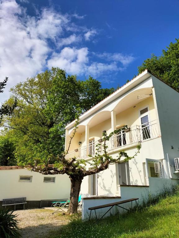 un bâtiment blanc avec un arbre devant lui dans l'établissement Gîte Ô fil du Tarn, à Lescure-dʼAlbigeois