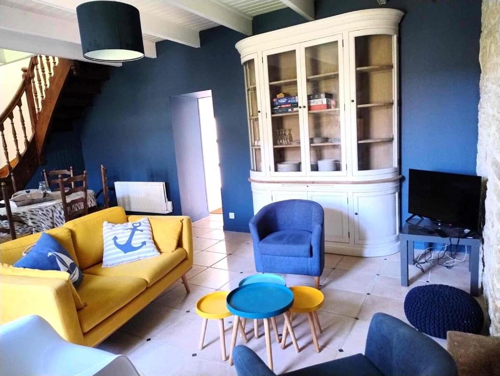 - un salon avec un canapé jaune et des fauteuils bleus dans l'établissement Cottage du Cap, à Fouesnant