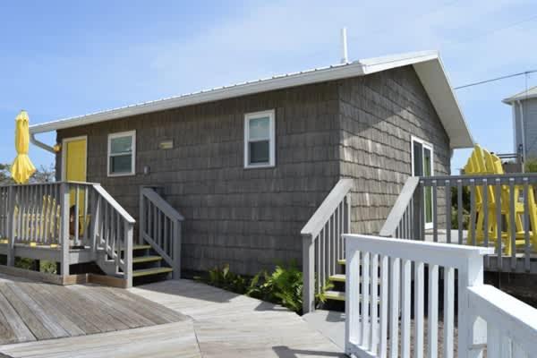 a house with a deck and stairs next to it at North Cape- Behing Trading Post - Pet Friendly in Cape San Blas