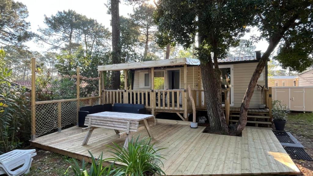 a tiny house with a wooden deck with a tree at Petit Cocon au Cap Ferret Camping les Embruns in Lège-Cap-Ferret