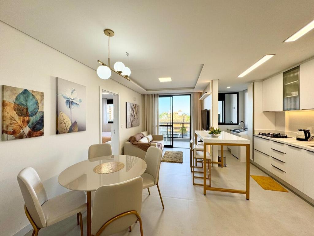 a kitchen and living room with a table and chairs at Palmas - Apto de praia moderno em HomeClub a 550m do mar in Governador Celso Ramos