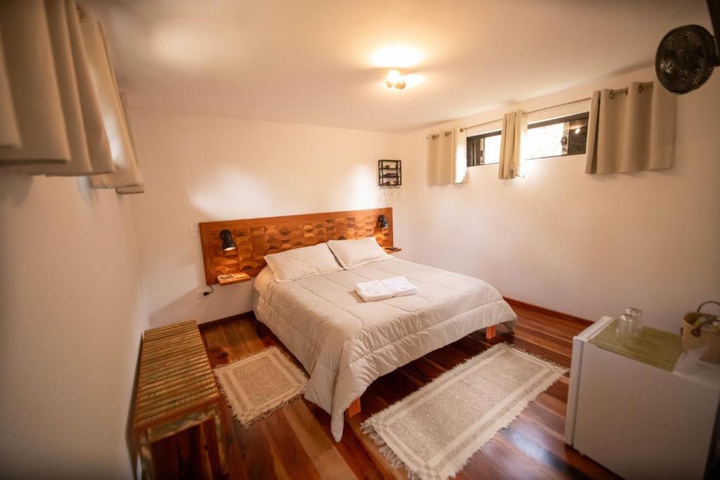 a bedroom with a bed with a wooden headboard at Suíte Jasmim branco in Campos do Jordão