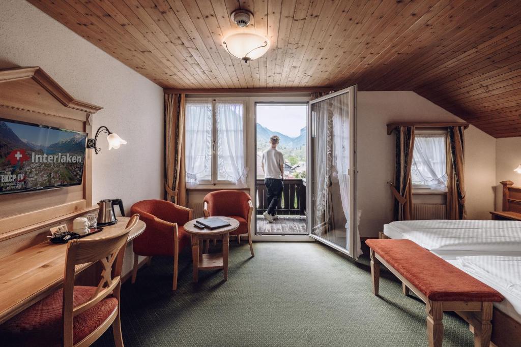 una camera d'albergo con un uomo che guarda fuori dalla finestra di Hotel Chalet Swiss a Interlaken