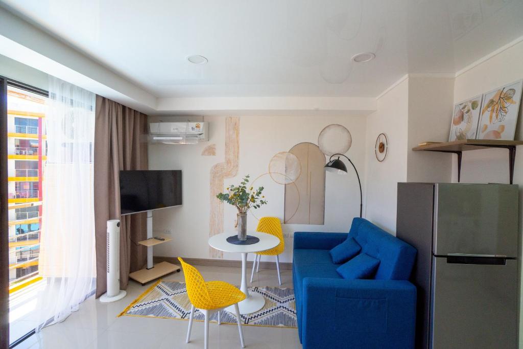 un soggiorno con un divano blu e sedie gialle di Pool View Tropic Studio a Ban Mai Salae