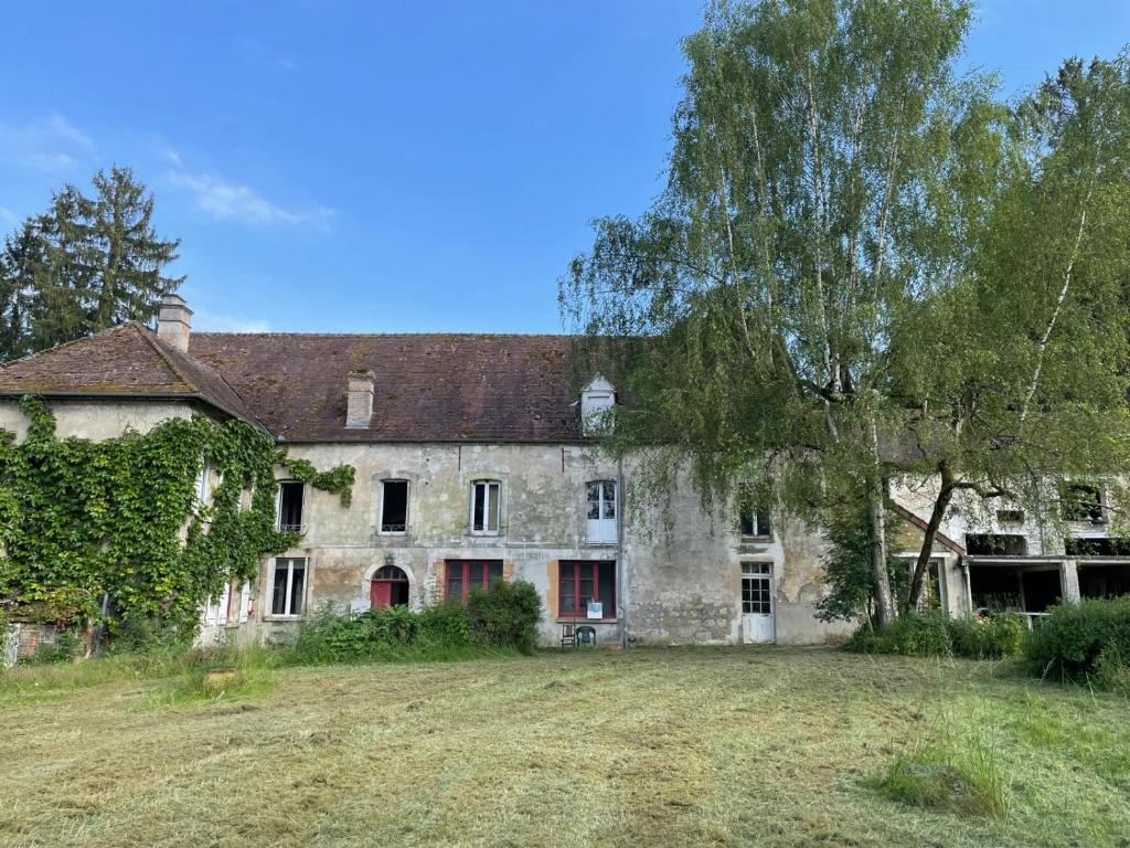 une vieille maison en pierre avec un arbre et un champ dans l'établissement Grande Maison Festive, à Loupeigne