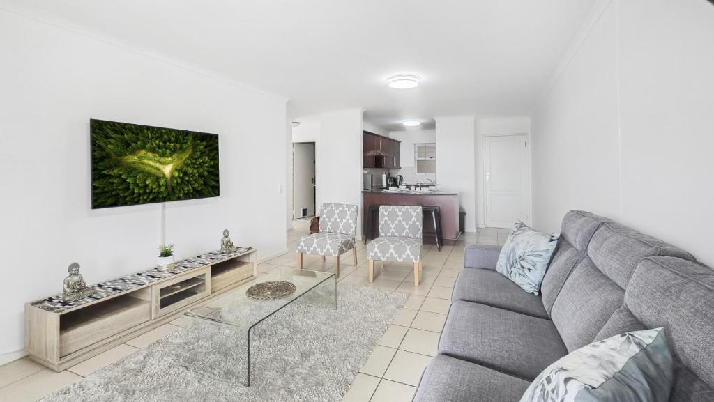 a living room with a gray couch and a table at Homely 3 Bedroom apartment in Villa Italia Century City in Cape Town