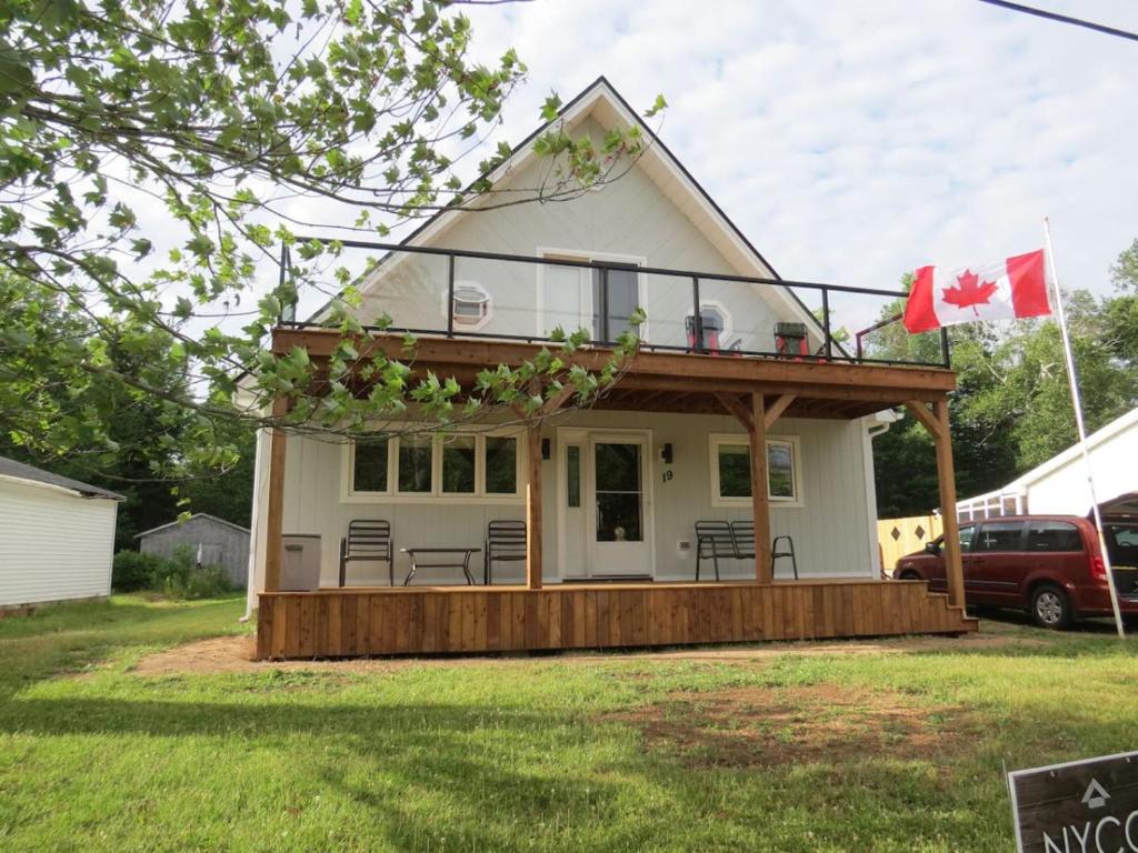 a house with a deck with a canadian flag at Get A Way Beach Chalet in Cocagne 