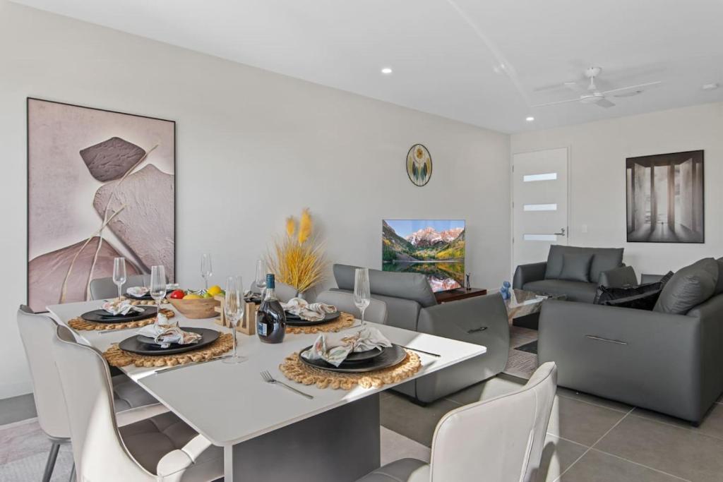 Un comedor con una mesa y sillas blancas. en Luxury 4BR Home with Pool Gym and BBQ in Helensvale, en Gold Coast