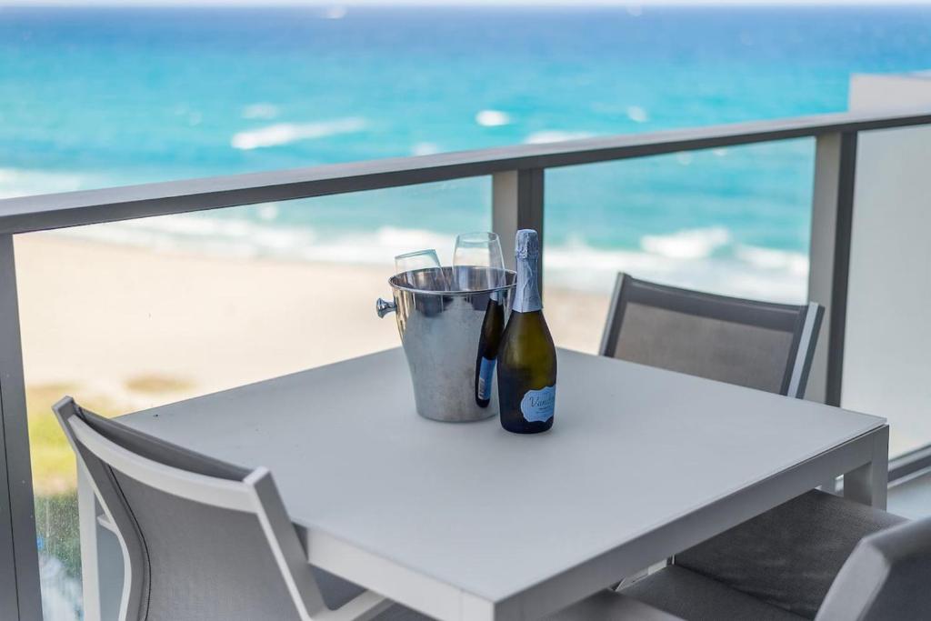 Una mesa blanca con una botella de vino y un cubo. en 2BR Tranquil Luxury by the Sea. Chic apt at Amrit, en Riviera Beach