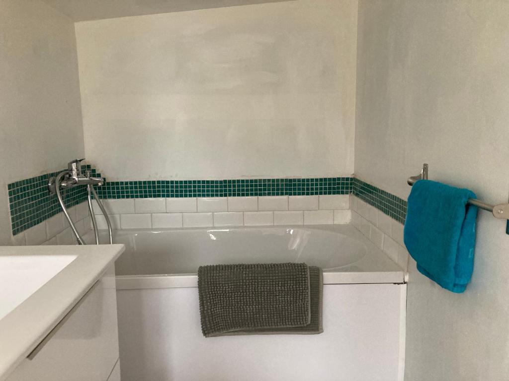 La salle de bains est pourvue d'une baignoire blanche et d'une serviette bleue. dans l'établissement JOLI T2 a ROQUEVAIRE, à Roquevaire