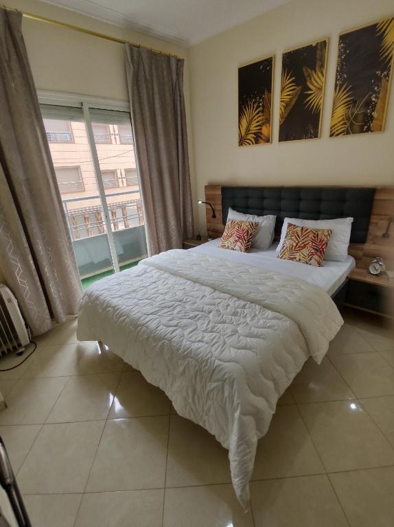 a bedroom with a large bed and a large window at Diar Kamiliya Meknès in Meknès
