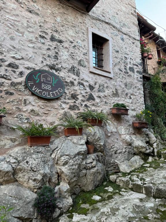 a stone building with a sign and plants on it at Il Vicoletto in Artena