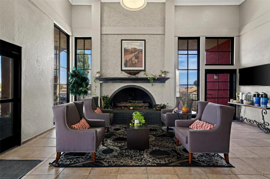 un salon avec des chaises et une cheminée dans l'établissement Best Western Desert Villa Inn, à Barstow