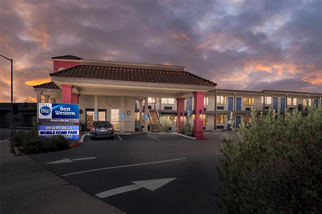 un bâtiment avec une voiture garée sur un parking dans l'établissement Best Western Desert Villa Inn, à Barstow
