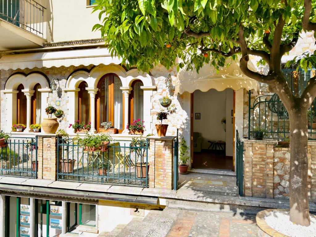 a building with potted plants and a tree at Casa Caterina in Taormina
