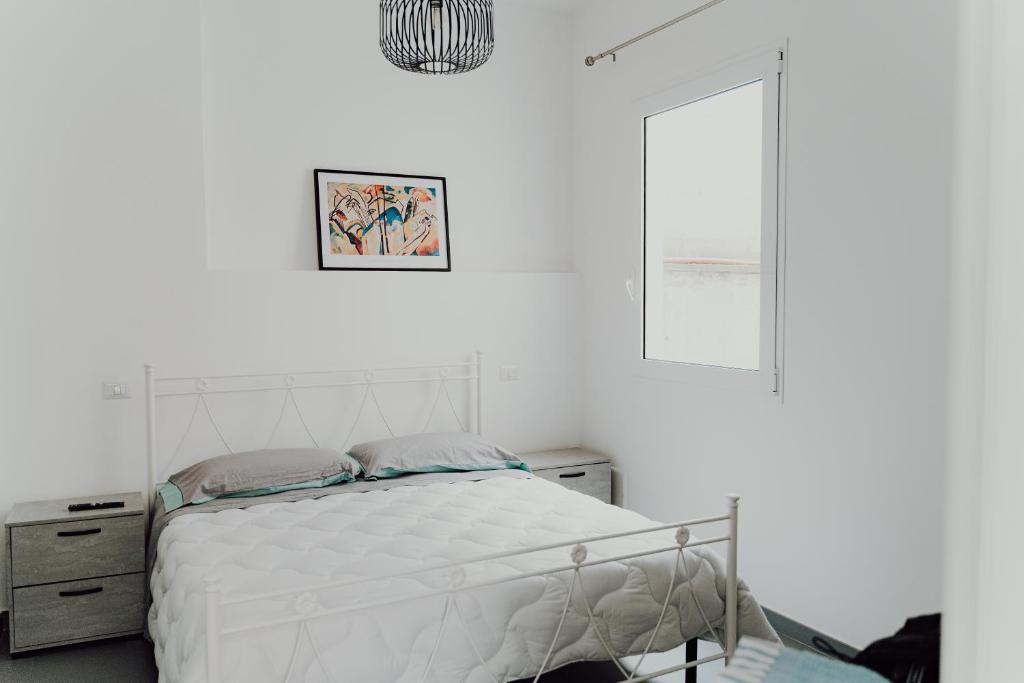 a white bedroom with a bed and a window at Cincin Casa in Francavilla Fontana