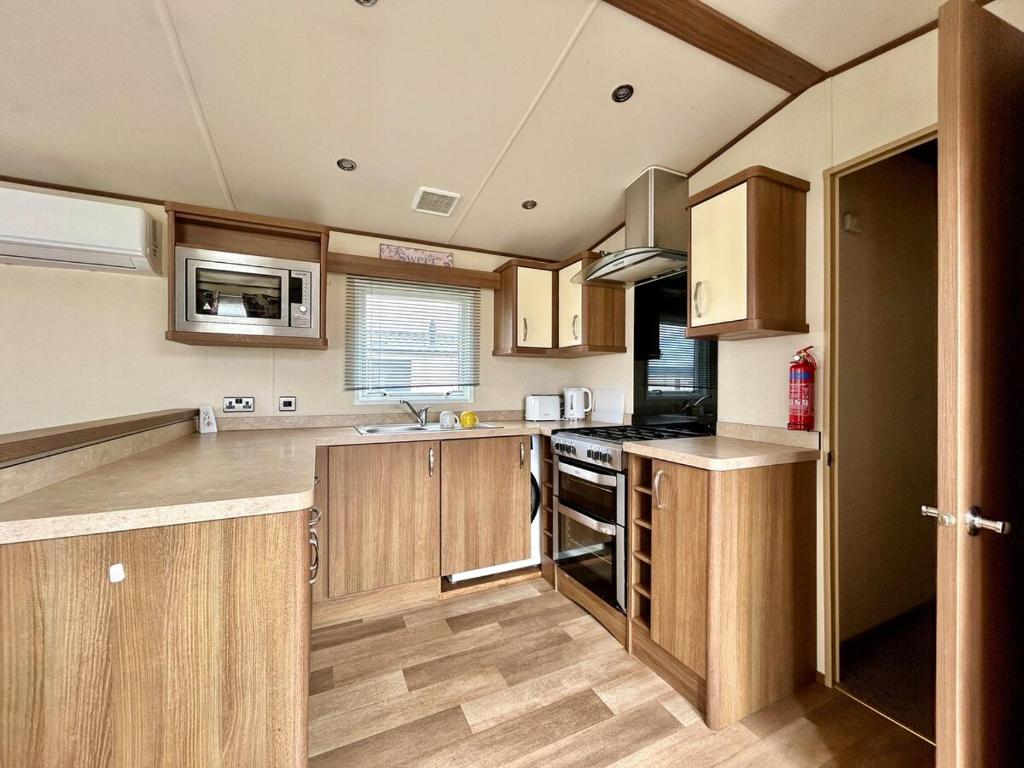 a kitchen with wooden cabinets and a stove top oven at VerbLake 5 Berth Caravan St Osyth Beach Holiday Park in Saint Osyth