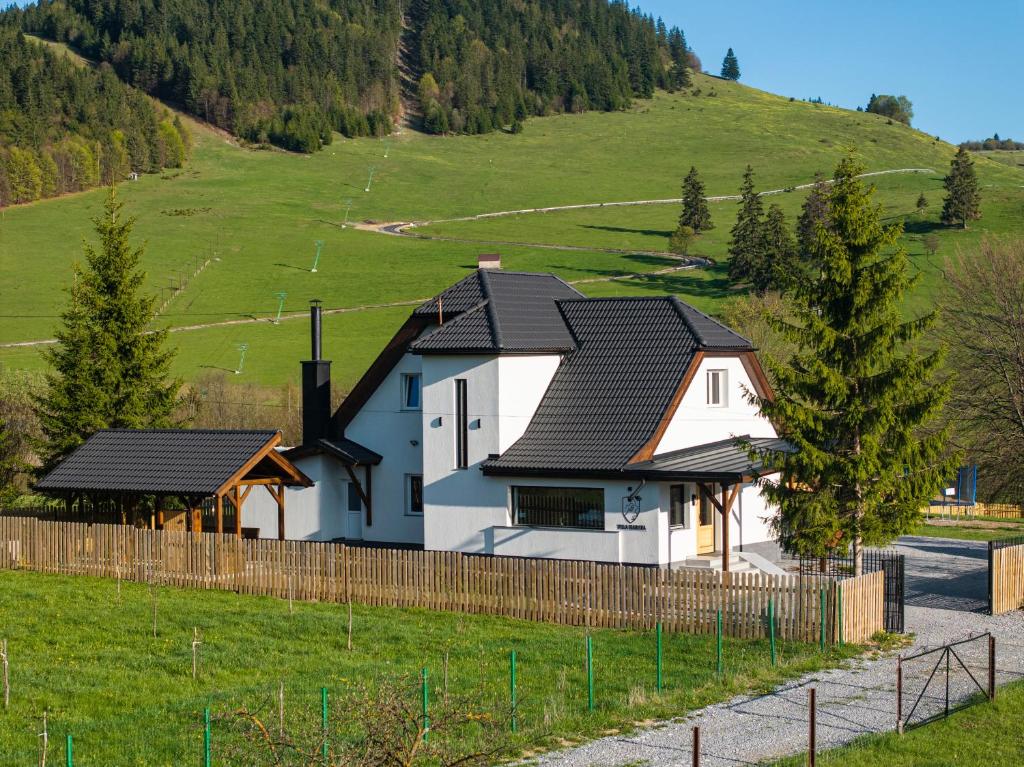 a white house with a black roof on a hill at Mariska Villa in Izvoru Mureşului
