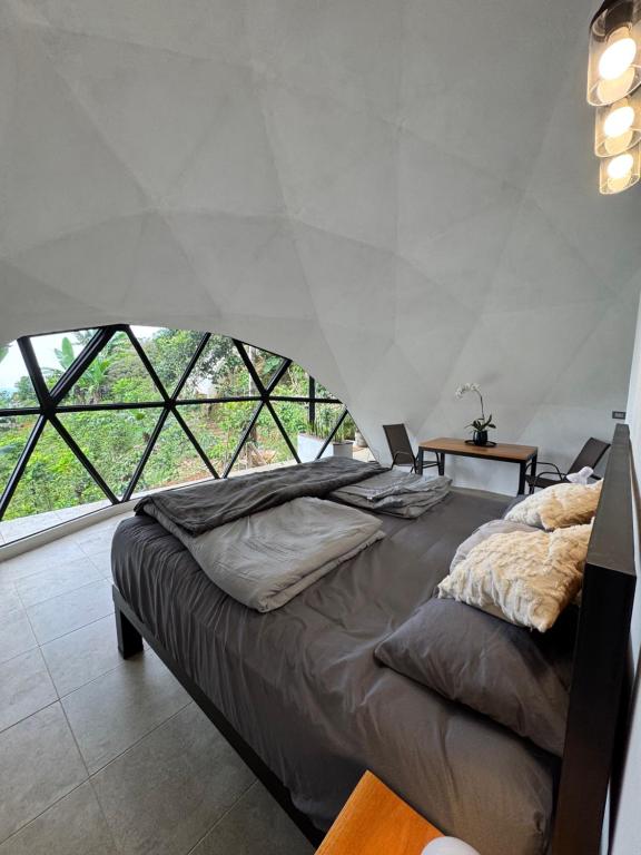 a bedroom with a large bed with a large window at Kayala Domes in La Ese