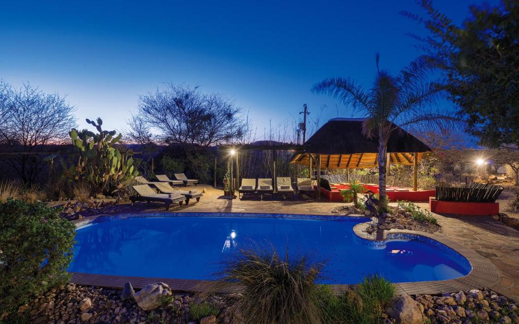 ein Schwimmbad in einem Garten in der Nacht in der Unterkunft Immanuel Wilderness Lodge in Windhoek