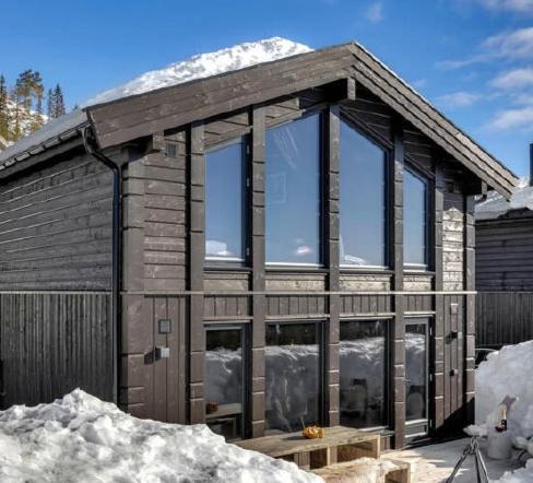 ein Holzhaus mit Glasfenstern im Schnee in der Unterkunft New, cozy cottage on Norefjell with stunning views in Noresund