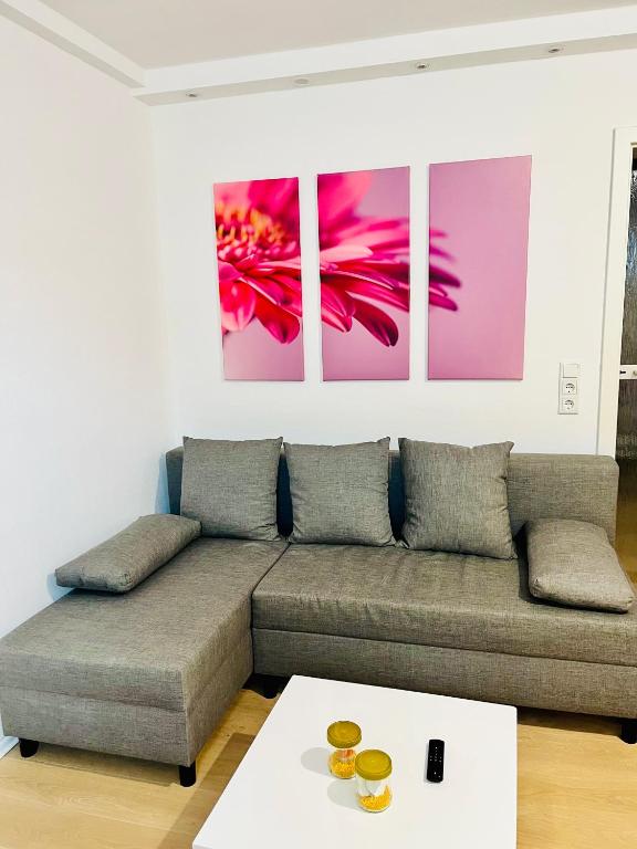 a living room with a couch and paintings on the wall at Ferienwohnung Sommerblüte in Schweich
