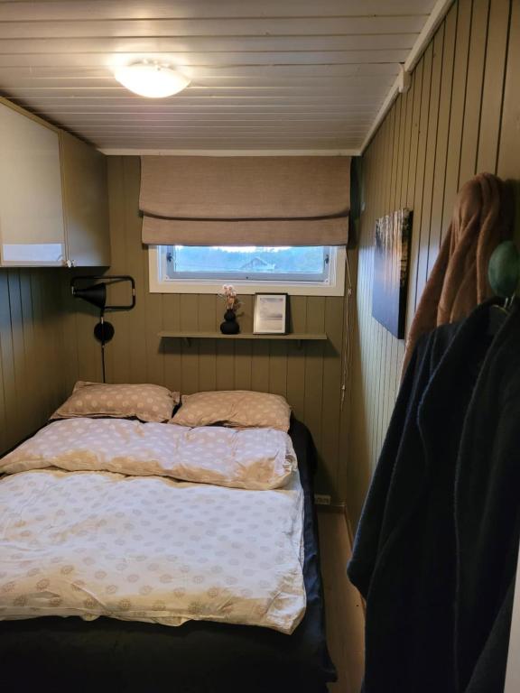 Un dormitorio pequeño con una cama y una ventana. en Emberland vannet , sveio, en Sveio