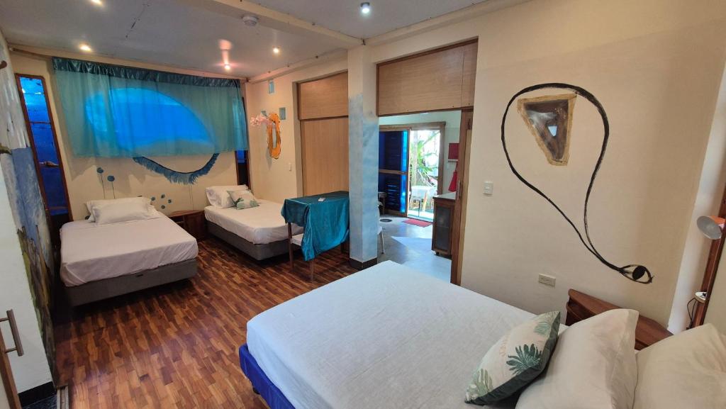 a hotel room with two beds and a mirror at Cozy Hosting Galapagos in Puerto Ayora
