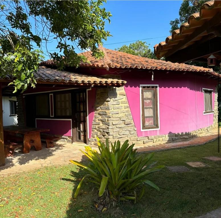 a pink house with a table in front of it at Refúgio a 100m da Praia Conforto e Lazer Completo in Prado