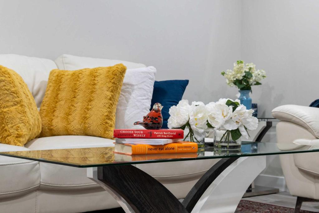 a coffee table with books and flowers on a couch at Modern 2BR Private Suite NW Near Airport & Amazing Shopping! Free Banff Pass, Netflix, Parking! in Calgary