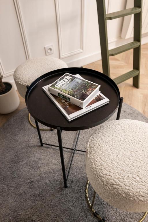 une table basse noire avec un magazine dessus à côté de deux chaises dans l'établissement Charmant studio à Pigalle, à Paris