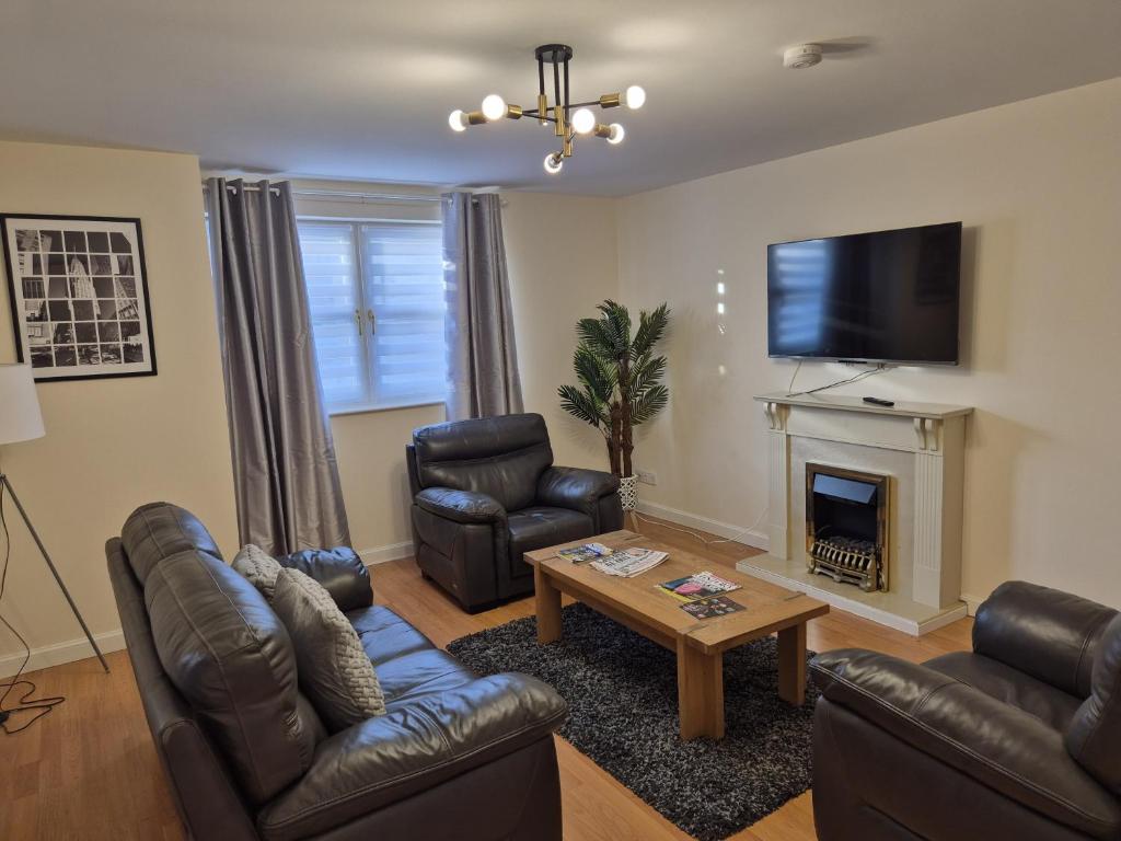 a living room with leather furniture and a fireplace at Spacious Modern 2-BR Apartment in Aberdeen City Centre in Aberdeen