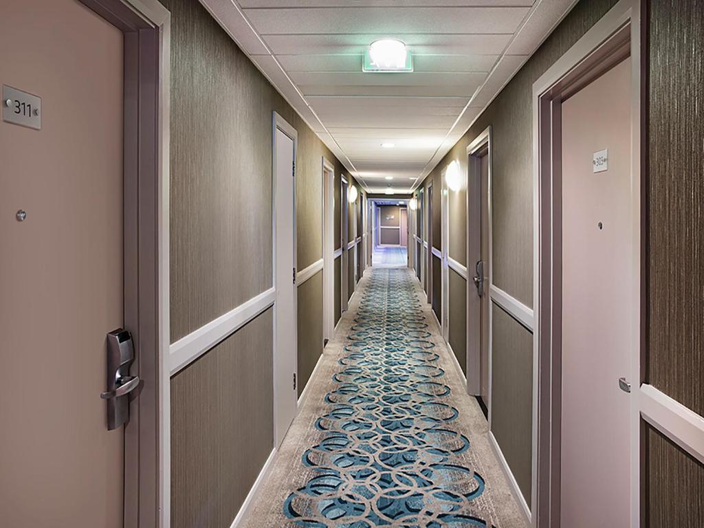 a hallway with a long aisle with blue and white carpet at Leonardo Hotel Brighton in Brighton & Hove