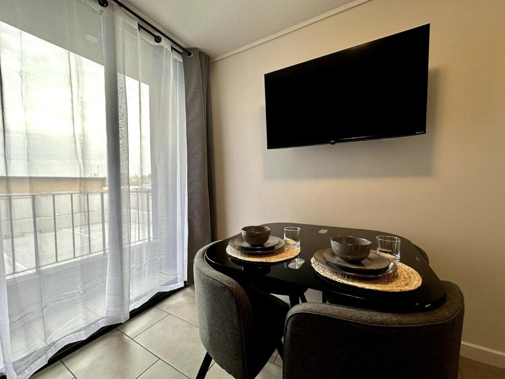a living room with a table with chairs and a television at Estudio cerca del Movistar Arena in Santiago