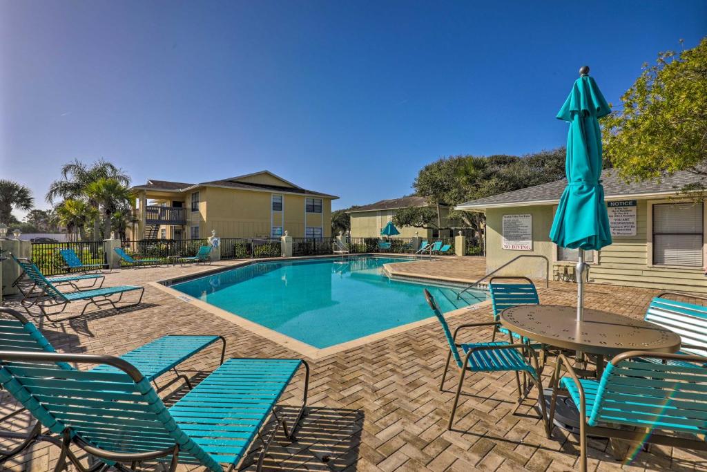 a pool with chairs and a table with an umbrella at Walk to St Augustine Beach! Condo w/ Pool Access in Saint Augustine Beach