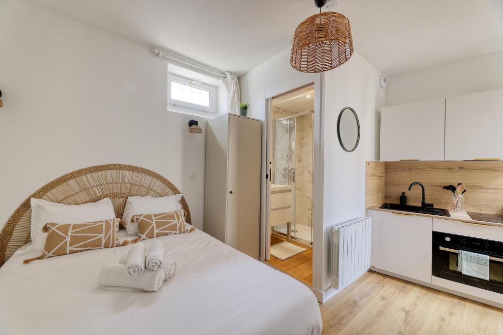 une chambre avec un lit blanc avec des serviettes dessus dans l'établissement Studio cosy - entre le Château des Ducs et le Jardin des Plantes, à Nantes